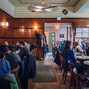 Café Grundmann - Gastronomie in Leipzig Blick in den Gastraum des Cafe Grundmann mit klassichen Kaffeehaus-Moebeln aus HolzSala Café Grundmann z klasycznymi meblami z drewnaView into the seating area at Café Grundmann with classic wooden coffee house furnitureDans la salle à manger du Café Grundmann, vue sur les meubles en bois typiques des maisons de dégustation de caféPohled do kavárny Café Grundmann s klasickým dřevěným a pro kavárny typickým nábytkem