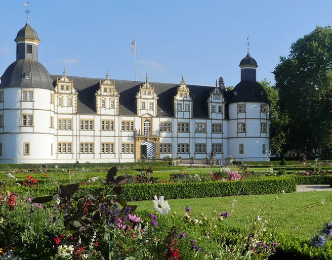 Schloß Neuhaus Historisches Schloss Neuhaus in Paderborn umgeben von gepflegtem Park, blühenden Blumenbeeten und Bäumen.