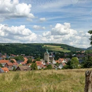 Blick auf Neuenbeken Neuenbeken mit seiner zentralen Kirche im Vordergrund, umgeben von Wiesen und bewaldeten Hügeln.