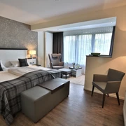 Zimmer Modernes Hotelzimmer mit zwei Einzelbetten, Sitzbereich und großen Fenstern mit Tageslicht.