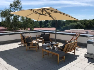 Geräumige Dachterrasse mit bequemen Holzmöbeln und Sonnenschirm lädt zum Entspannen ein.