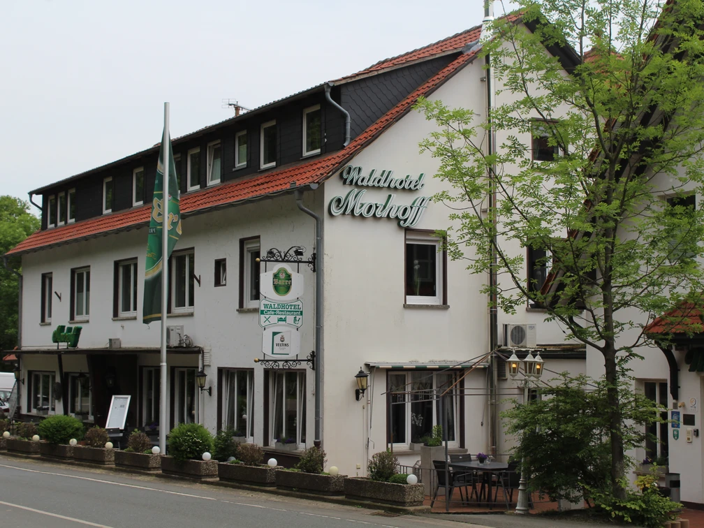 Balkes Morhoff Waldhotel Morhoff in ländlicher Umgebung, umgeben von Bäumen, mit rotem Dach und weißen Wänden.