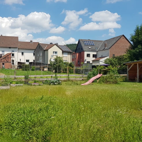 schutzhuette_georgsgarten_ottbergen_2.jpg Eine kleine hölzerne Schutzhütte im Grünen, umgeben von Häusern und einladendem Sonnenschein.