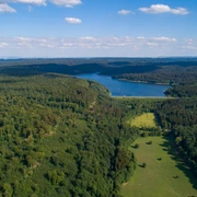 Weitläufige Wälder umgeben den Aabach-Stausee, dessen blaues Wasser die Landschaft prägt.