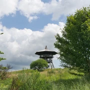 Der Eggeturm am Preußischen Velmerstot Eggeturm am Velmerstot in hügeliger Landschaft, umgeben von grünen Wiesen und Bäumen.