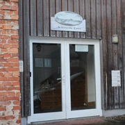 Eingang einer Ferienwohnung mit hölzerner Fassade, rechte Klinkerwand und gläserner Doppeltür.