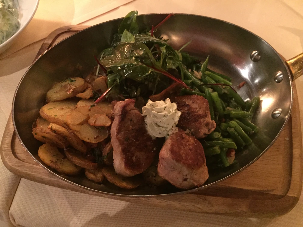 Pfannengericht Ein pfannengebratenes Gericht mit knusprigen Bratkartoffeln, saftigem Fleisch, Bohnen und Salatblatt.