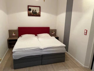 Steimkes Landhotel Zimmer Ein Doppelbett in schlichtem, modernem Zimmer mit Wandbildern und Nachtlampen auf Holztischen.