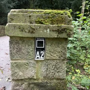 Steinbrücke mit moosbewachsenem Pfeiler des Zedlingswegs, umgeben von üppiger Waldvegetation.