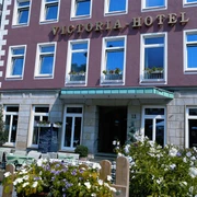 Fassade des Victoria Hotels mit blühenden Blumen im Vordergrund und klassischer Architektur.
