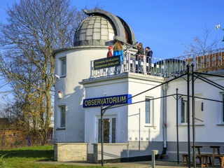 Astronomisches Zentrum Schkeuditz - Sehenswürdigkeiten in der Leipzig Region Blick von außen auf das Planetarium Schkeuditz, auf dessen Dach einer Gruppe junger Menschen die Funktionsweise des Teleskops erklärt wird, Freizeit, Wissenschaft, Leipzig für Gruppen