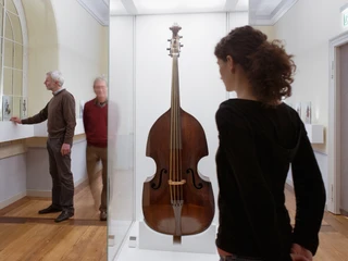 Bach-Museum - Museen in Leipzig Eine junge Frau steht vor einem Kontrabass der Exponat in der Ausstellung im Bach Museum der Musikstadt Leipzig ist, Kultureinrichtung, Musikstadt, Ausstellung