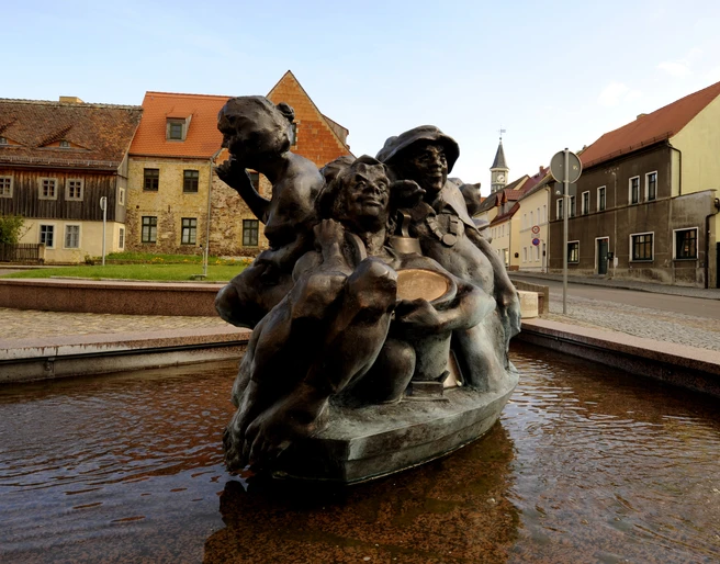 Schildbürgerdenkmal in Schildau ©W. Siesing Sackhupperbrunnen im Vordergrund und Häuserzeile am Markt in Schildau, Kultur, Sehenswürdigkeiten