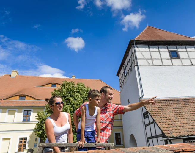 Burg Düben - Leipzig und Region mit Kindern Eine Familie mit Kind steht auf dem Gelände der Burg Düben im Sonnenschein und schaut sich die Umgebung an, Familie, Ausflug, Freizeit, Kultur