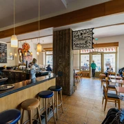 Café Cantona - Gastronomie Leipzig Blick in den gemütlichen Gastraum des Café Cantona mit Holzbar und breiter Fensterfront