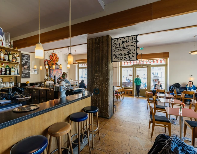Café Cantona - Gastronomie Leipzig Blick in den gemütlichen Gastraum des Café Cantona mit Holzbar und breiter Fensterfront