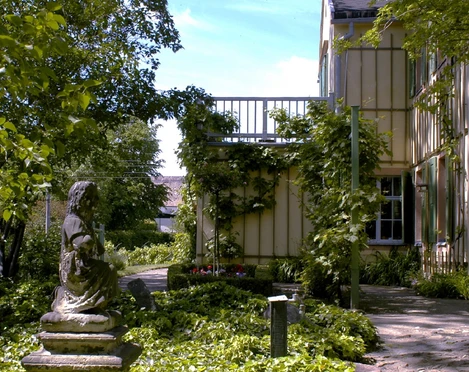 klassizistischer Göschengarten Der Göschengarten zeigt ein idyllisches Eck mit einer Statue zwischen üppigem Grün und einem Fachwerkhaus.