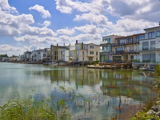 Lagune Kahnsdorf am Hainer See Moderne Wohnhäuser mit großen Fenstern und Balkonen spiegeln sich im ruhigen Wasser der Lagune Kahnsdorf.