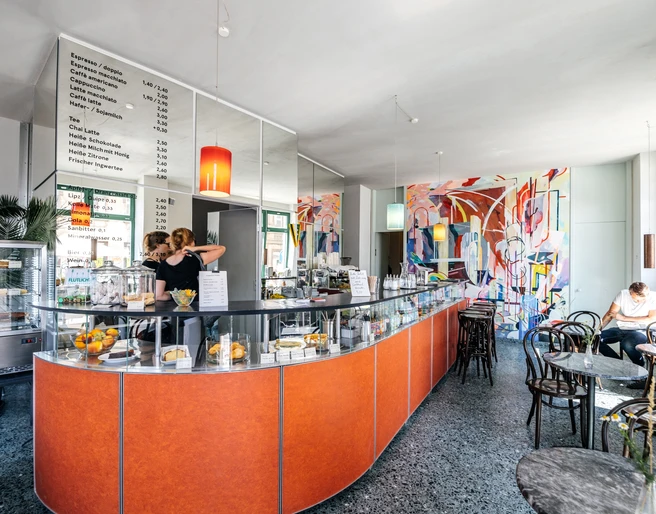 INO Café - Cafés in Leipzig Blick auf den Bar-Bereich des INO Cafés mit seiner Theke, der Bestuhlung und den Utensilien hinter der Bar, cafe, kaffeehaus, genuss, gastronomie