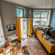 Jimmy Orpheus - Cafés in Leipzig Blick inn das farbenfrohe Jimmy Orpheus-Café aus der Vogelperspektive; mit Blick auf Sitzbereich, Theke, Fensterfronten