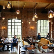 Kaiserbad - Gastronomie in Leipzig Blick in den großen Saal des Kaiserbad, mit Fokus auf den modernen Leuchten, den Backsteinwänden und den Gästen, welche ihre Mahlzeiten genießen, restaurant, kulinarik, gastronomie, freizeit