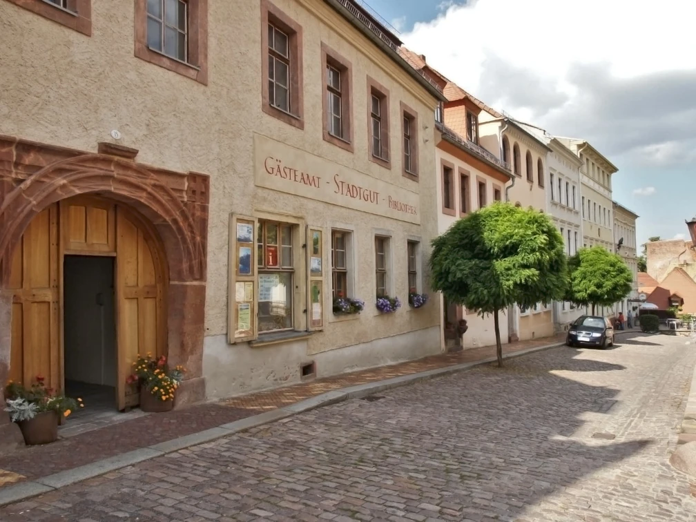 Gästeamt Leisnig im Stadtgut Das Bild zeigt die Aussenansicht des Stadtguts, die Fassade ist ockerfarben und es hat ein imposantes Tor.The picture shows the exterior of the manor house, the façade is ochre-coloured and it has an imposing gate.