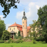Schloss Machern im Schlosspark Das Schloss Machern erhebt sich prachtvoll inmitten üppiger Natur, mit seinen charakteristischen Türmen und einem gepflegten Garten davor.