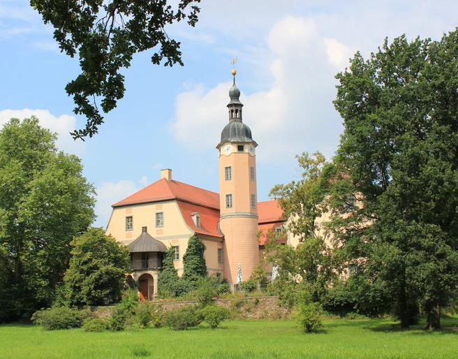 Schloss Machern im Schlosspark Das Schloss Machern erhebt sich prachtvoll inmitten üppiger Natur, mit seinen charakteristischen Türmen und einem gepflegten Garten davor.
