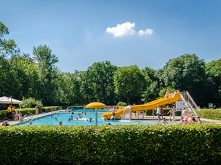 Schreberbad Leipzig - Freizeiterlebnisse in der Leipzig Region Blick auf das Hauptschwimmbecken im Schreberbad, mit gelber Rutsche und vielen Badegästen an einem Sommertag, Freizeitaktivität, Badespaß