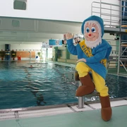 Schwimmhalle Eilenburg - Schwimmbäder in der Leipzig Region Das Schwimmbecken der Schwimmhalle Eilenburg, das Maskottchen im Zwerg-Kostüm sitzt auf einem der Startblöcke und winkt, Schwimmbäder, Aktiv, Freizeit