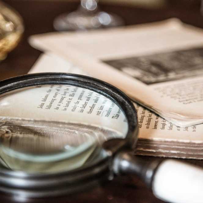 Eine Lupe und mehrere Unterlagen bei sherLOCKRooms - Erlebnisse in Leipzig