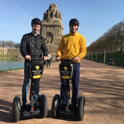 Stadtstromer Segwaytour - Erlebnisanbieter in Leipzig Blick auf das Völkerschlachtdenkmal Leipzig im Hintergrund und zwei Männer auf Segways die eine Stadtführung des Erlebnisanbieters Stadtstromer besuchen