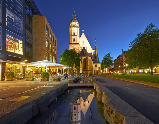 Thomaskirche Leipzig - Musikstadt Leipzig Blick auf die angestrahlte Thomaskirche in der Abend-Dämmerung, links davor das Brauhaus mit Freisitz und rechts davon die grüne Thomaswiese mit Bäumen, Kultureinrichtung, Freizeit, Musik, Bach