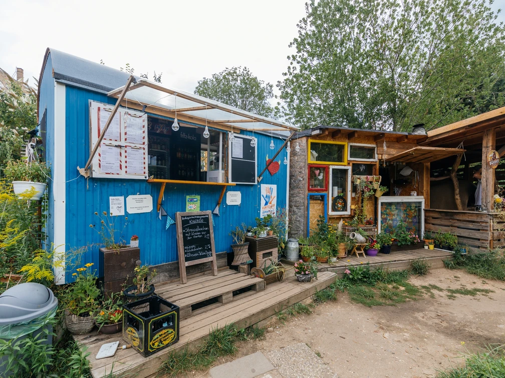 Zum Wilden Heinz - Cafés in Leipzig Blick auf den blauen Ausschank-Wagen sowie den angrenzenden Holzverschlag im "Zum Wilden Heinz"-Biergarten, freisitz, gastronomie