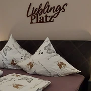 moderne_ferienwohnung_lieblingsplatz2.jpg Ein stilvoll eingerichtetes Schlafzimmer mit einem Doppelbett, dekorativen Schmetterlingskissen und sanfter Beleuchtung.