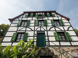 Altes Doktorhaus in Haan-Gruiten Fachwerkhaus mit grünen Fensterläden, historische Architektur, vor klar blauem Himmel.
