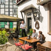 Erfrischung im Biergarten der Kutscherstuben in Wülfrath-Düssel Ein Gastro-Mitarbeiter serviert im sonnigen Biergarten zwei Gästen auf einer Terrasse Getränke.