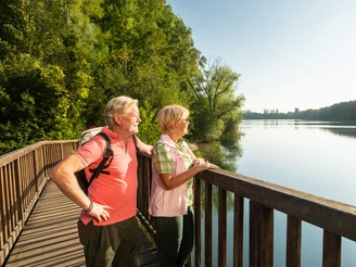 Auf einer Brücke am Menzelsee bei Hilden Seniorenpaar genießt den Blick vom Holzsteg auf den ruhigen, weitläufigen Menzelsee bei Hilden.