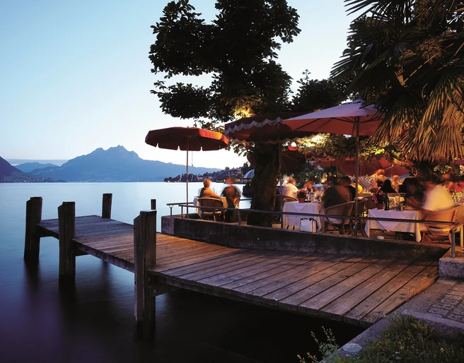 Restaurant-Pizzeria SeeHotel Gotthard Gartenterrasse direkt am See in der AbenddämmerungGarden terrace directly on the lake at duskTerrasse de jardin au bord du lac au crépuscule