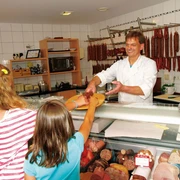 Metzger reicht Mädchen Ahle Wurscht - © Gutes aus Waldhessen e.V.