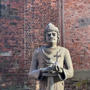 Karl der Große Steinfigur von Karl dem Großen vor einer Backsteinmauer, hält Kreuz und Modell einer Kirche in Händen.