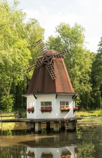 Heidberger Mühle im Ittertal bei Haan Historische Windmühle im Grünen, umgeben von Bäumen, mit einem kleinen Teich im Vordergrund.