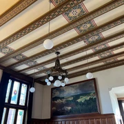 Ratssaal Rathaus Hoya Holzvertäfelter Ratssaal mit prunkvollem Kronleuchter, gemusterten Deckenbalken und bemaltem Wandbild.