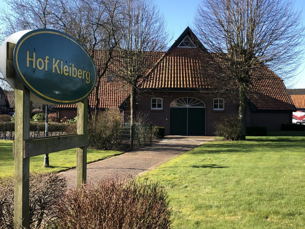 Hof Kleiberg Das Bild zeigt den Hof Kleiberg mit einem traditionellen Backsteingebäude und grünem Rasen im Vordergrund.