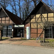 Zwei traditionelle Fachwerkgebäude im Naturpark Steinhude mit großen Fenstern und Naturpark-Beschilderung.