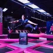 Hi-Fly Trampolin Park in Hilden Ein Trampolinpark mit leuchtenden pinken Elementen und fröhlich springenden Personen, die Spaß haben.