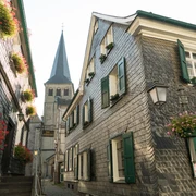 Oberstadt Mettmann mit Stadtgeschichtshaus und St. Lambertus Kirche Fachwerkhäuser mit Schieferfassaden und grünen Fensterläden in Mettmanns Oberstadt, St. Lambertus im Hintergrund.
