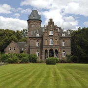 Marienburg mit Marienburgpark in Monheim am Rhein Eine imposante Backsteinburg mit kleinem Turm, umgeben von gepflegtem Rasen und Bäumen.