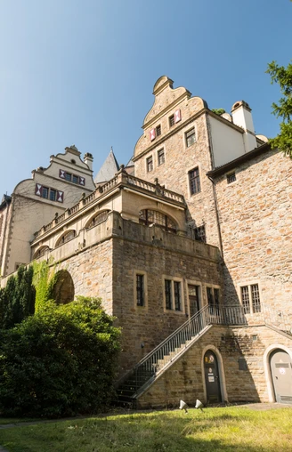 Gebäude Schloss Landsberg mit kleinem Weg und Bäumen. Historisches Schloss mit Treppe, umgeben von Bäumen und einem schmalen Weg, aufgenommen bei klarem Himmel.
