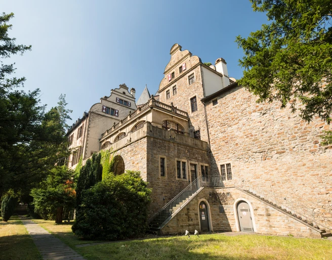 Gebäude Schloss Landsberg mit kleinem Weg und Bäumen. Historisches Schloss mit Treppe, umgeben von Bäumen und einem schmalen Weg, aufgenommen bei klarem Himmel.